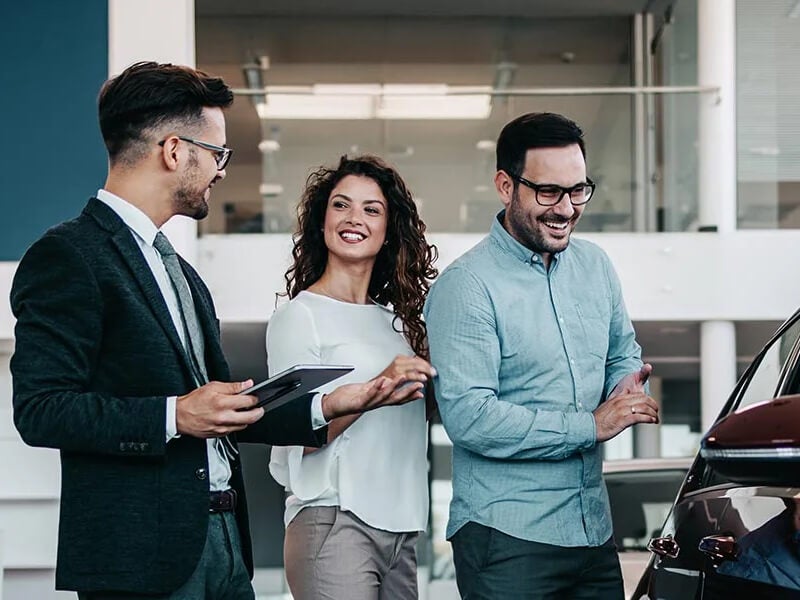 Couple Chatting with Salesperson in Dealership Showroom